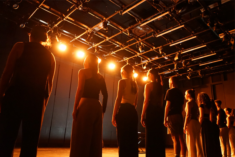 bailarinos em linha a cantar em cena