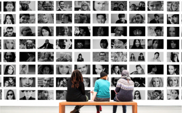 3 jovens a olhar para parede repleta de fotos de caras de pessoas